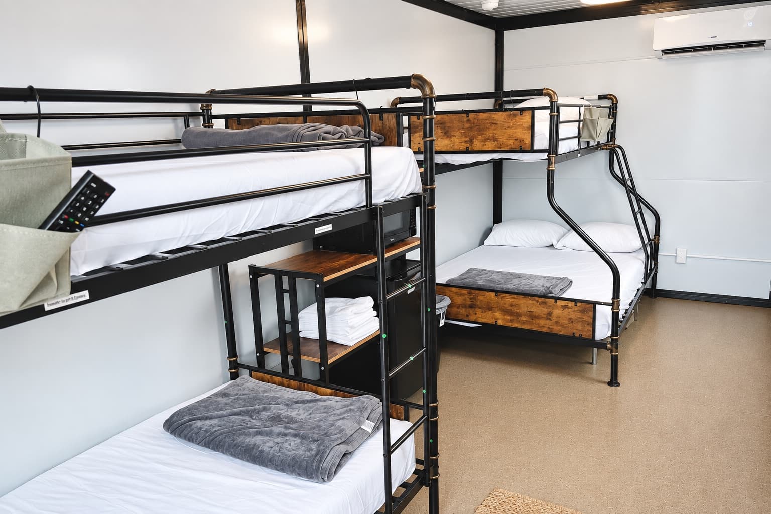 Bunkhouse interior with two bunk beds, a mini-fridge, microwave and a mini-split