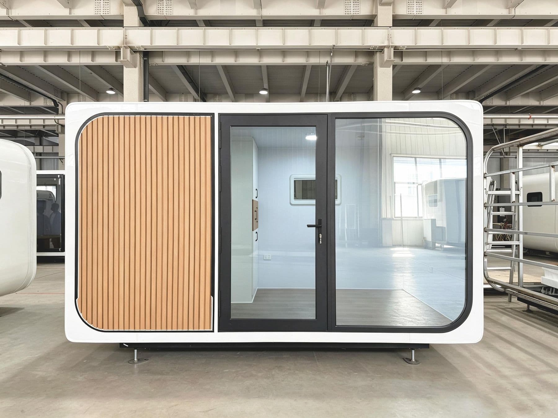 X1AppleHouse front view in the factory: wood-slat panel and full-height glass entry